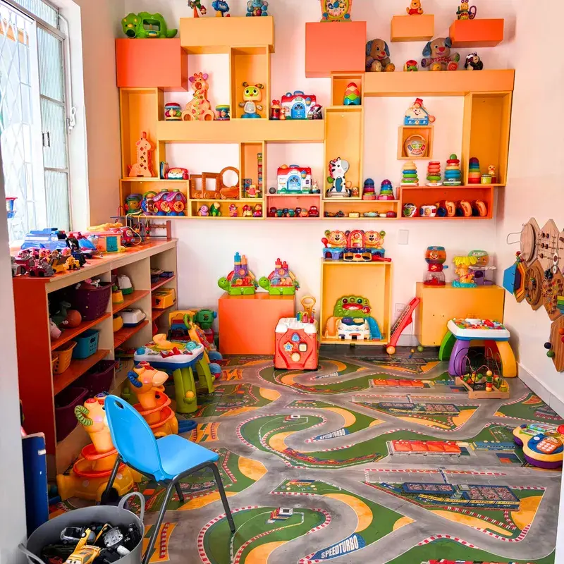 Sala com prateleiras de brinquedos coloridos e tapete de pista