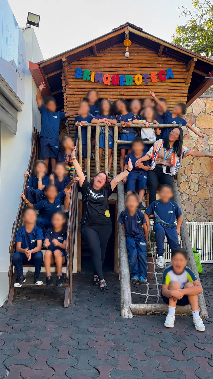 Uma turma de escola, com as professoras, na casinha de madeira da Brinquedoteca