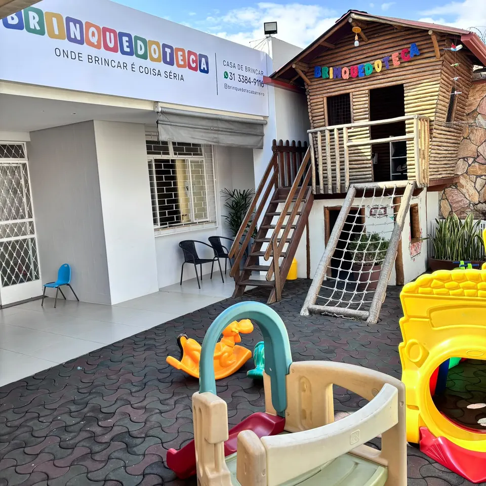 A fachada da Brinquedoteca Barreiro, com a casinha de madeira e os brinquedos do quintal